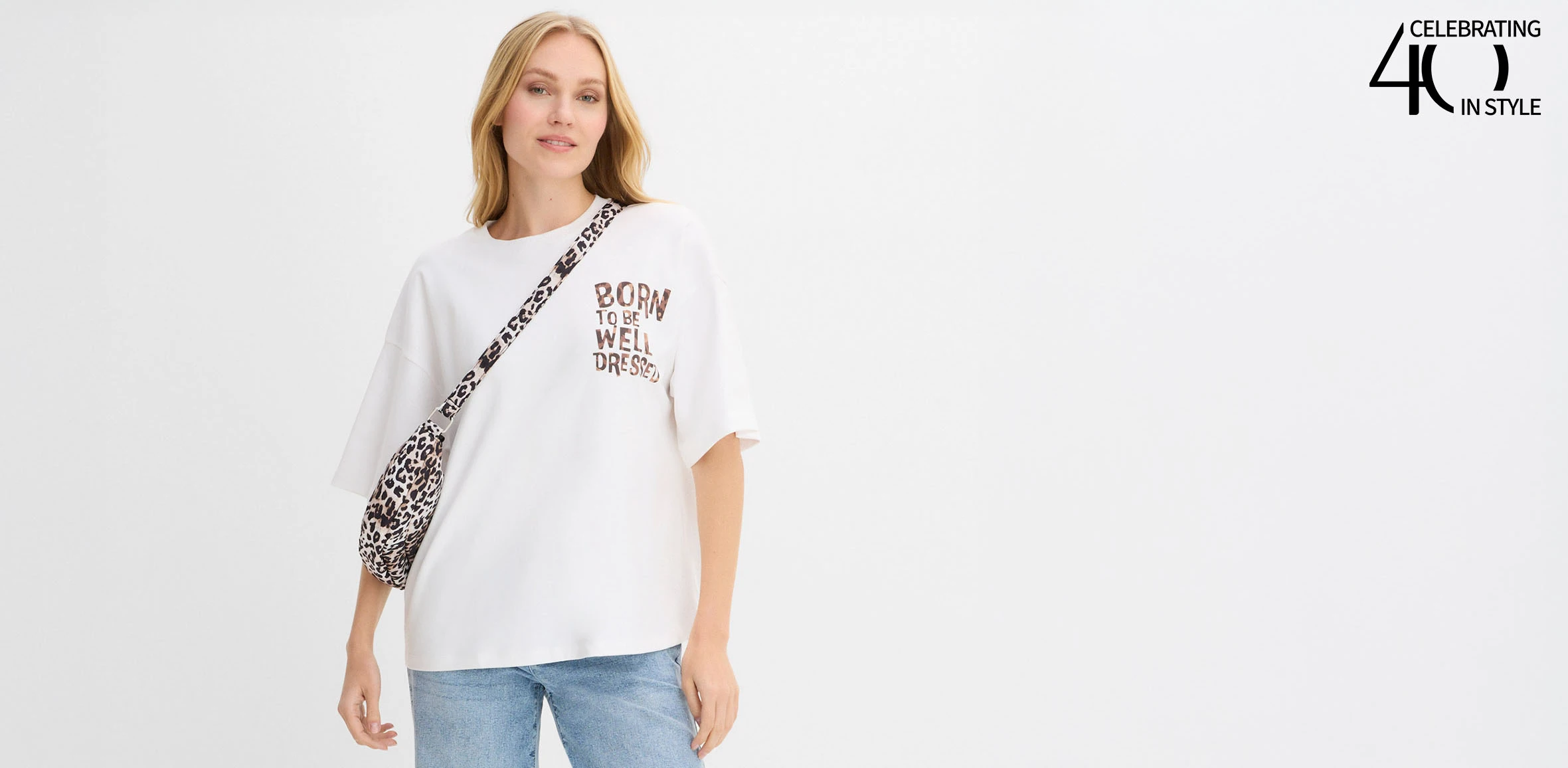 Tricou alb cu imprimeu și detalii cu model leo, asortat la blugi albaștri, în stil casual.