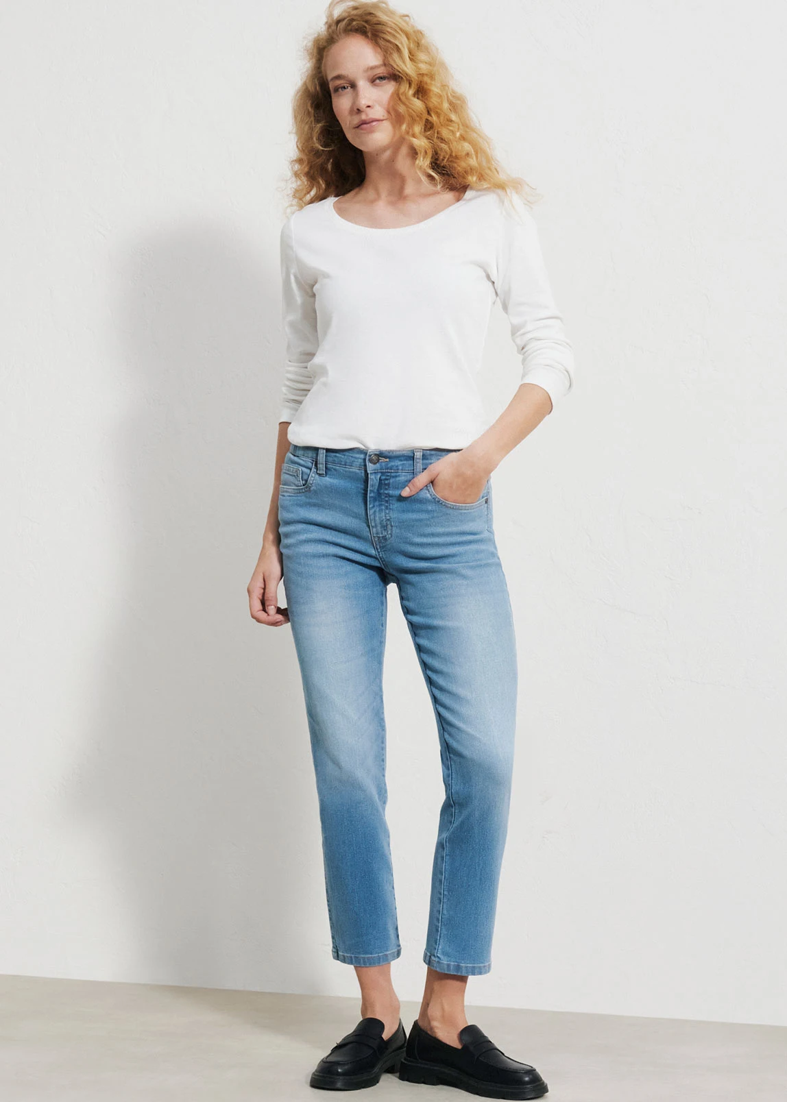 Look lejer cu un tricou alb, blugi bleu deschis și cizme maro.