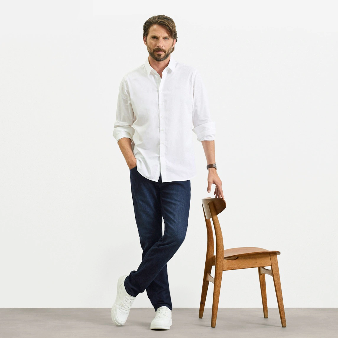 Cămașă albă, blugi închiși la culoare Slim Fit și adidași albi.
