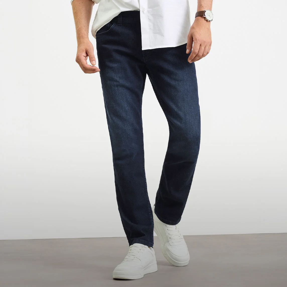 Cămașă albă, blugi închiși la culoare Slim Fit și adidași albi.
