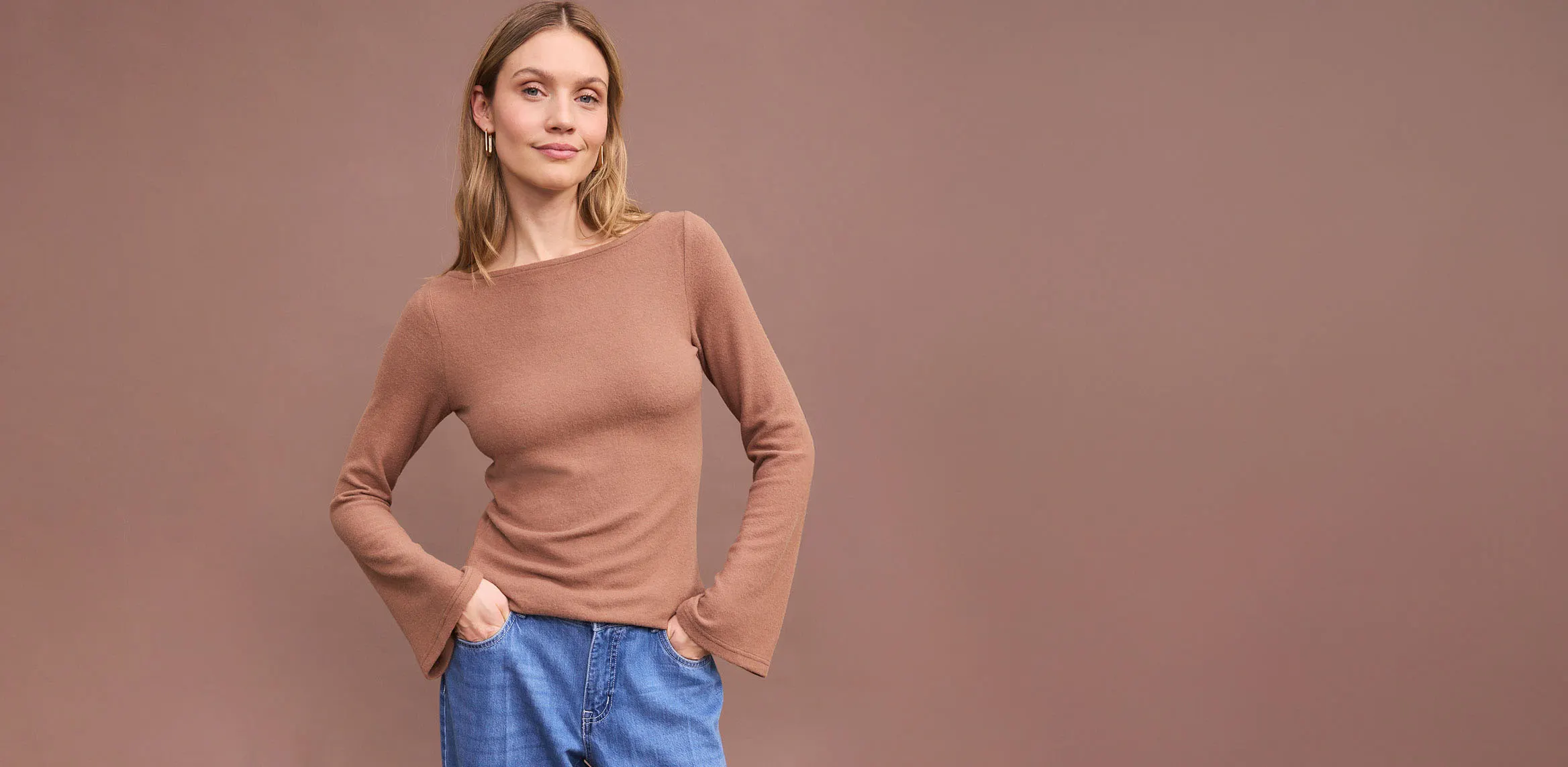 Bluză maro cu mâneci lungi și blugi albaștrii comozi.