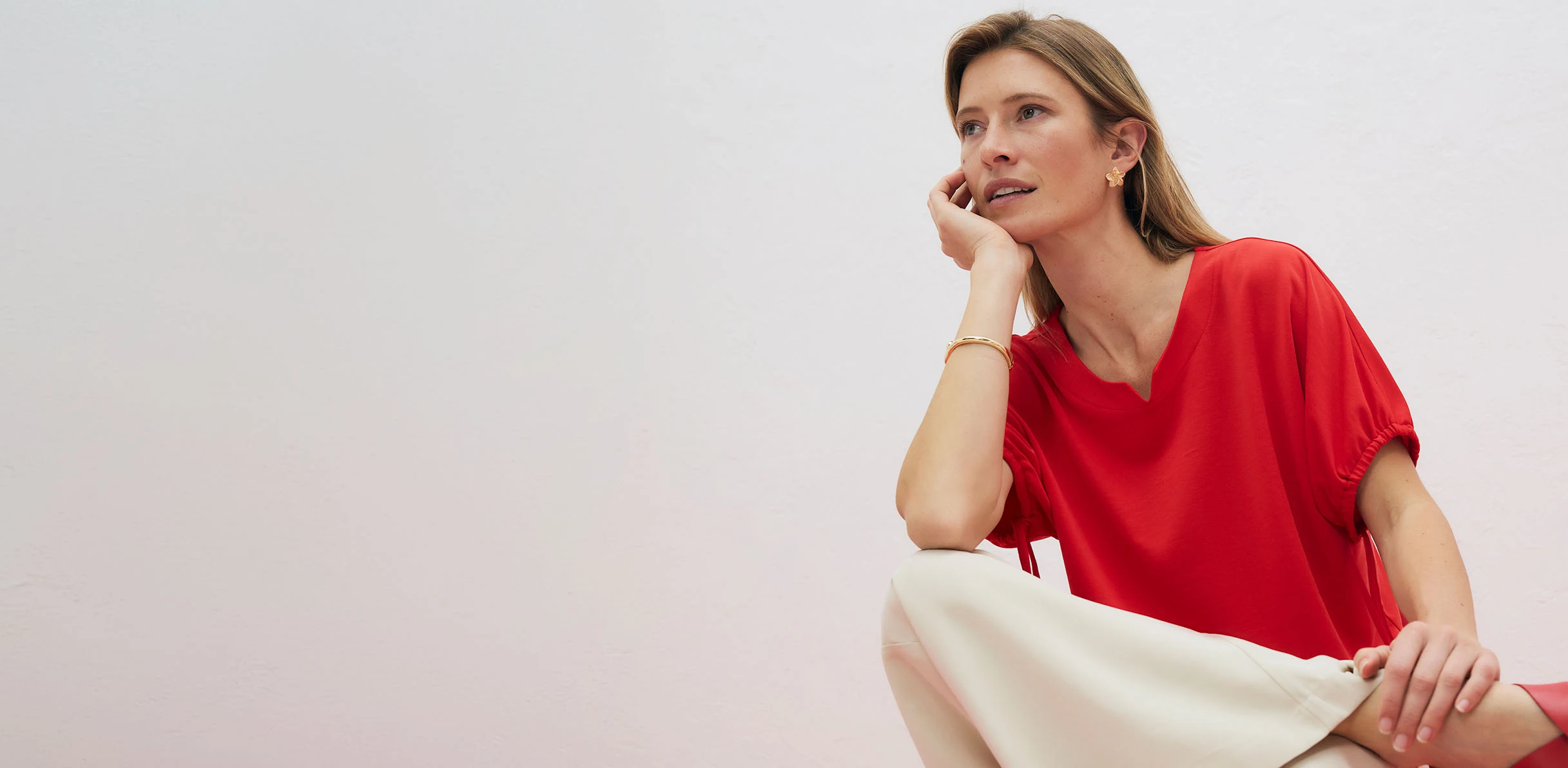 Tricou roșu elegant cu decolteu în V, combinat cu pantaloni deschiși la culoare.