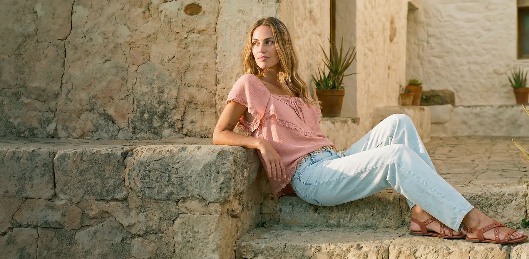 Bluză roz pastel cu volane și blugi bleu.