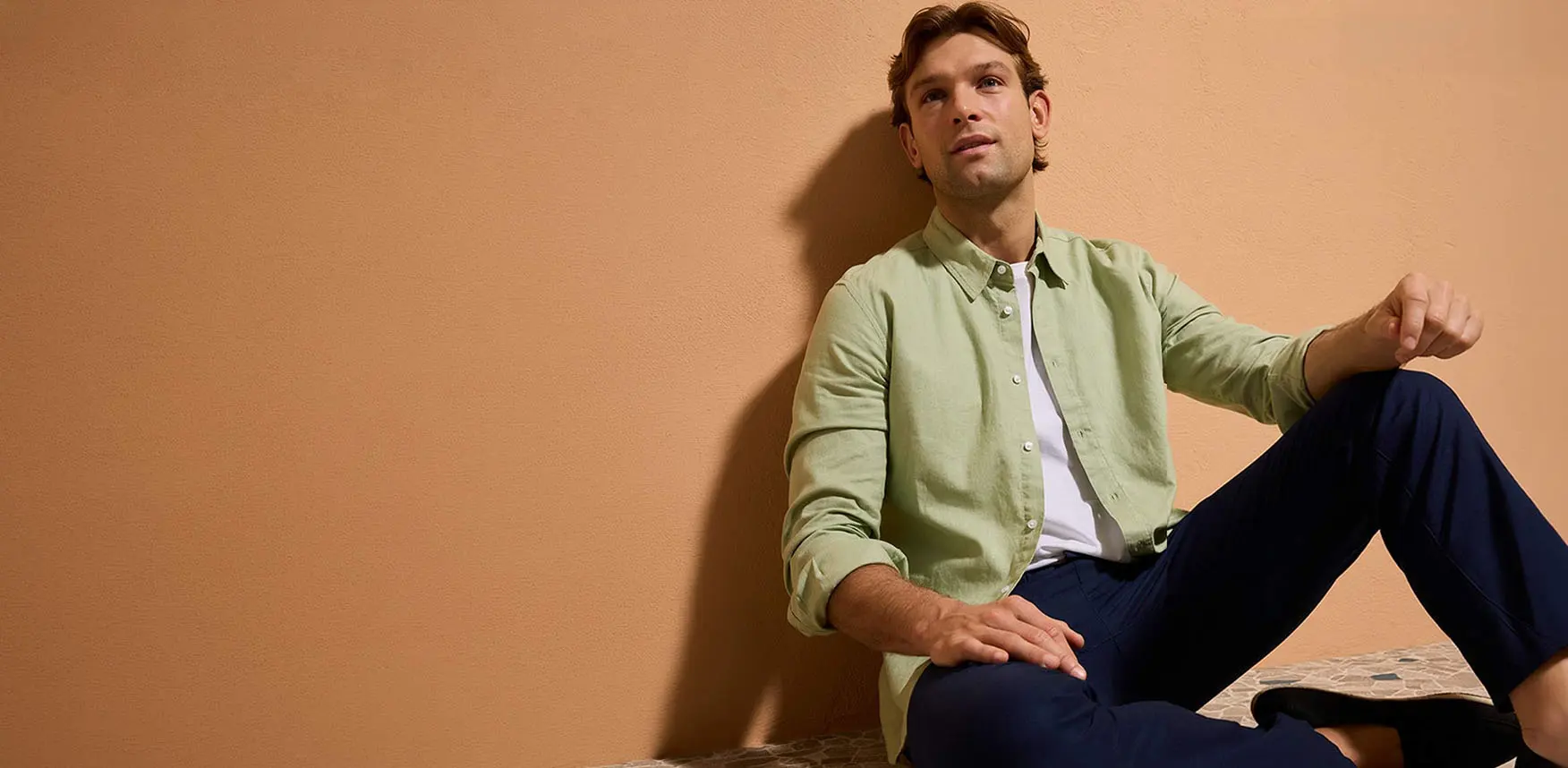 Cămașă verde pastel, pantaloni bleumarin și încălțăminte casual.