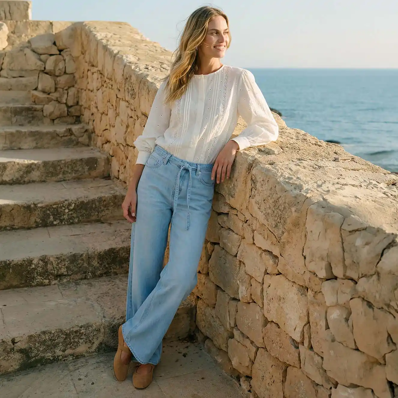 Bluză albă vaporoasă combinată cu blugi bleu.