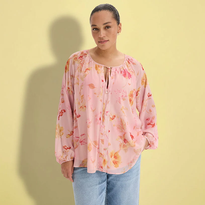 Bluză roz pal cu model floral și blugi lejeri.