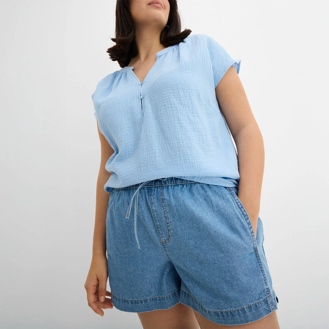 Parte de sus bleu fără mâneci cu fermoar și șort lejer de blugi pentru un look de vară lejer.