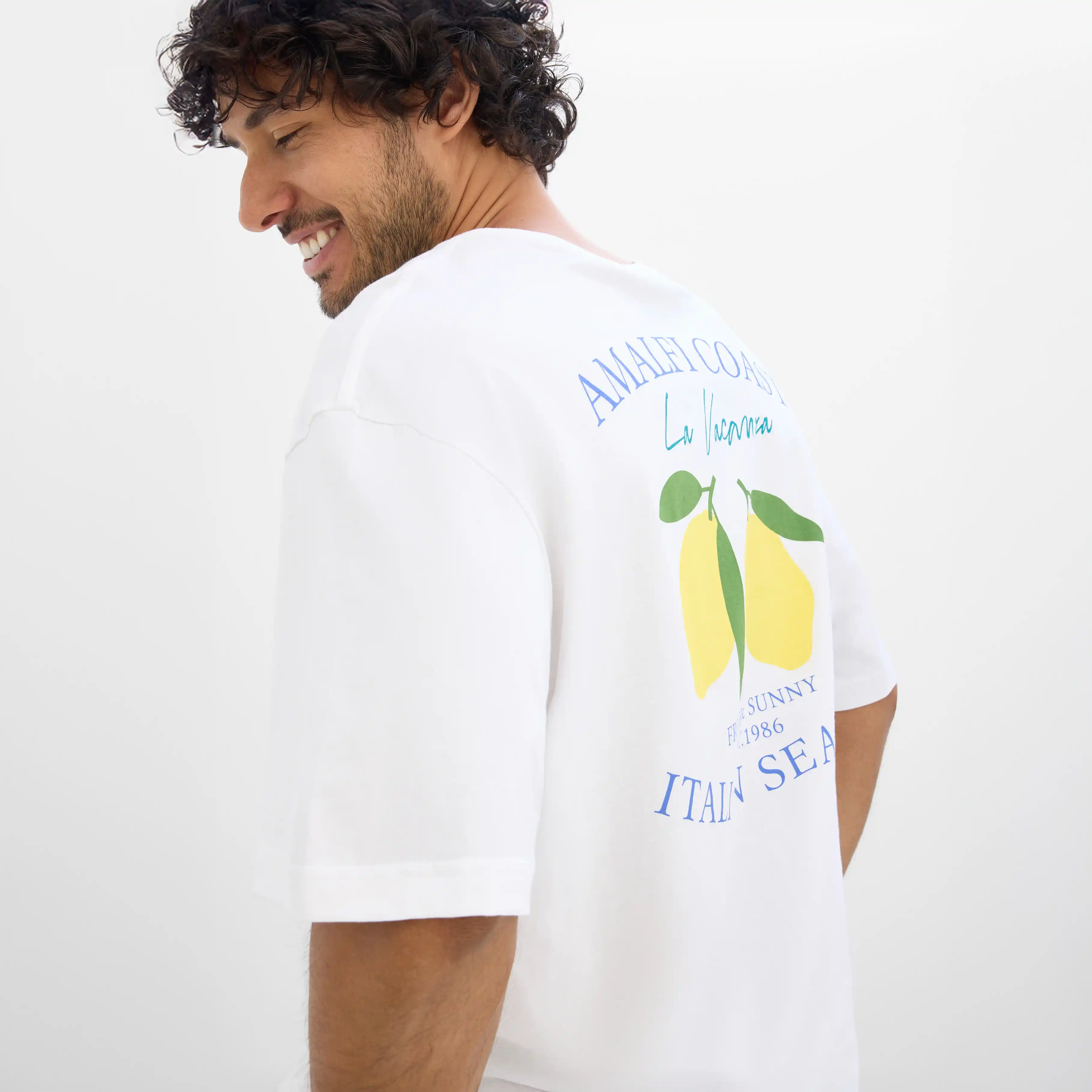 Tricou alb cu motiv lămâie și inscripție pe spate.