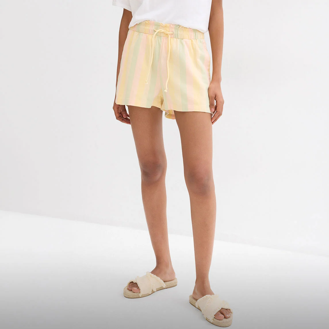 Șort pastel cu dungi, tricou alb și sandale comode din bast pentru zile fierbinți.
